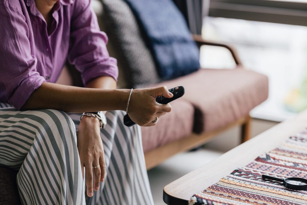 Person sitting on a coach holding TV remote