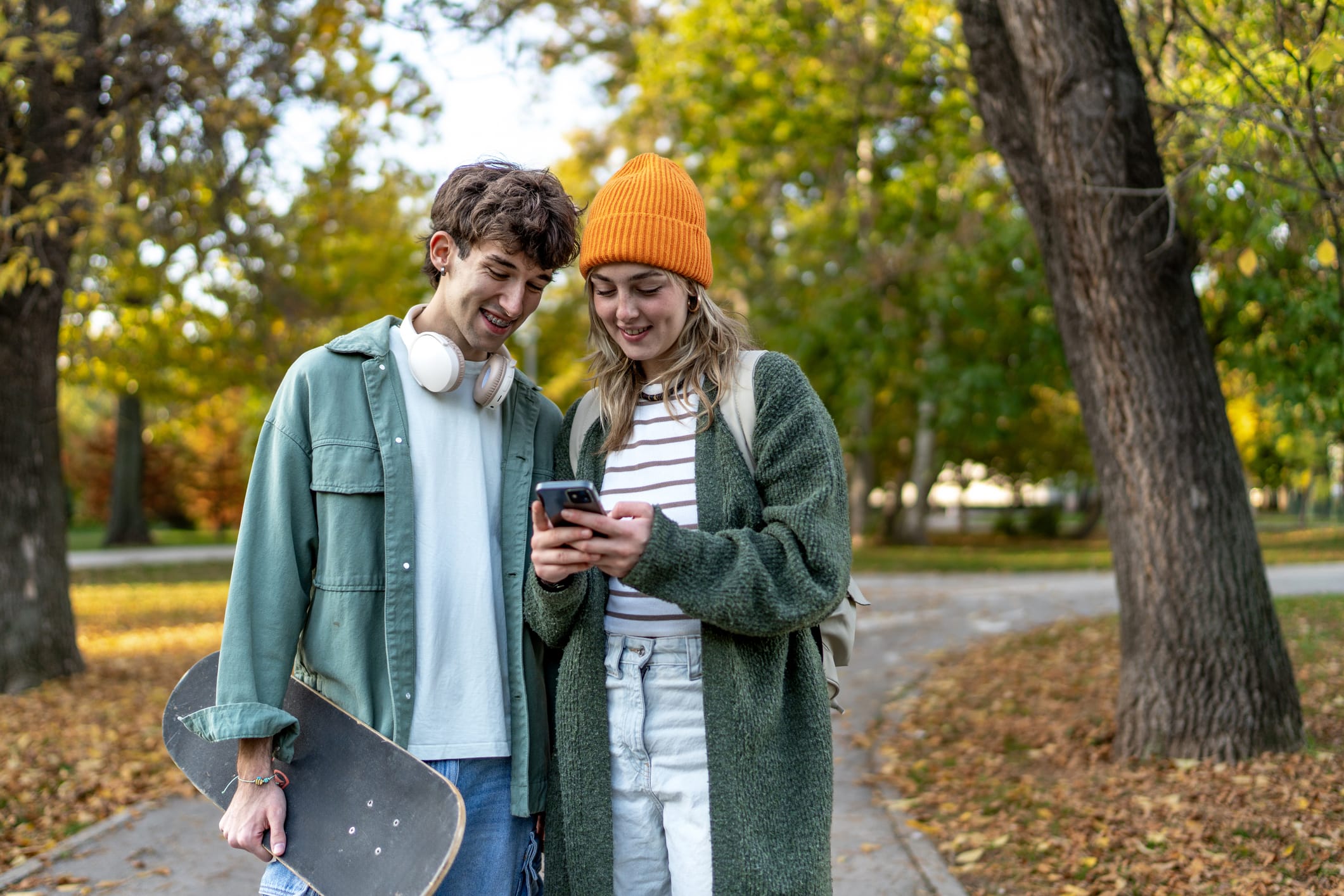 Young Gen Z Couple looking at phone in park
