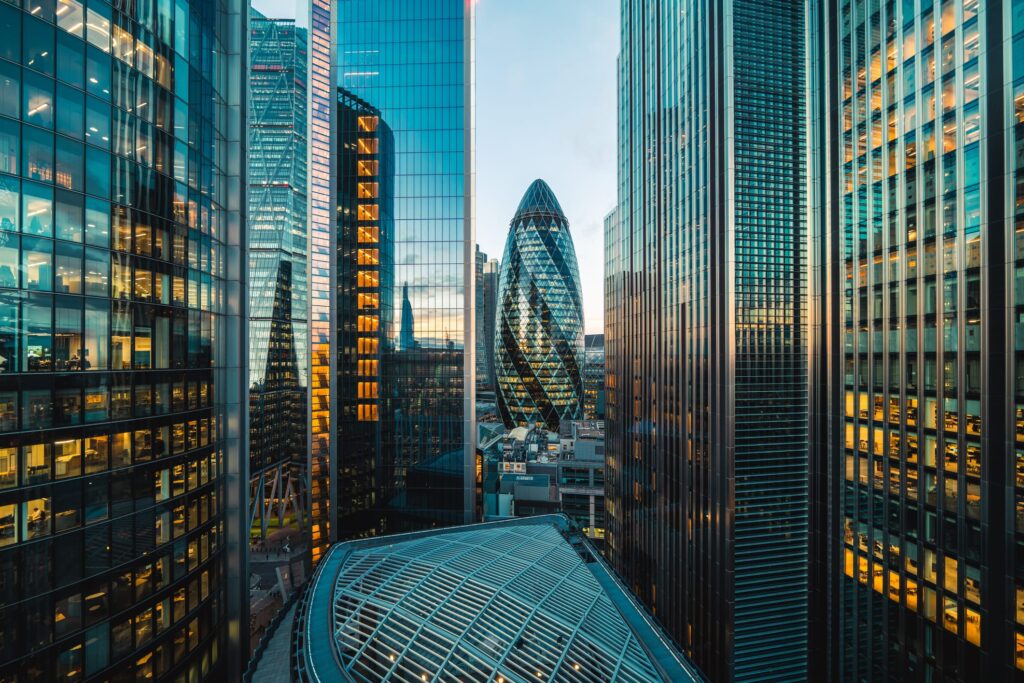 City of London office towers lit at dusk, with the Gherkin at the center
